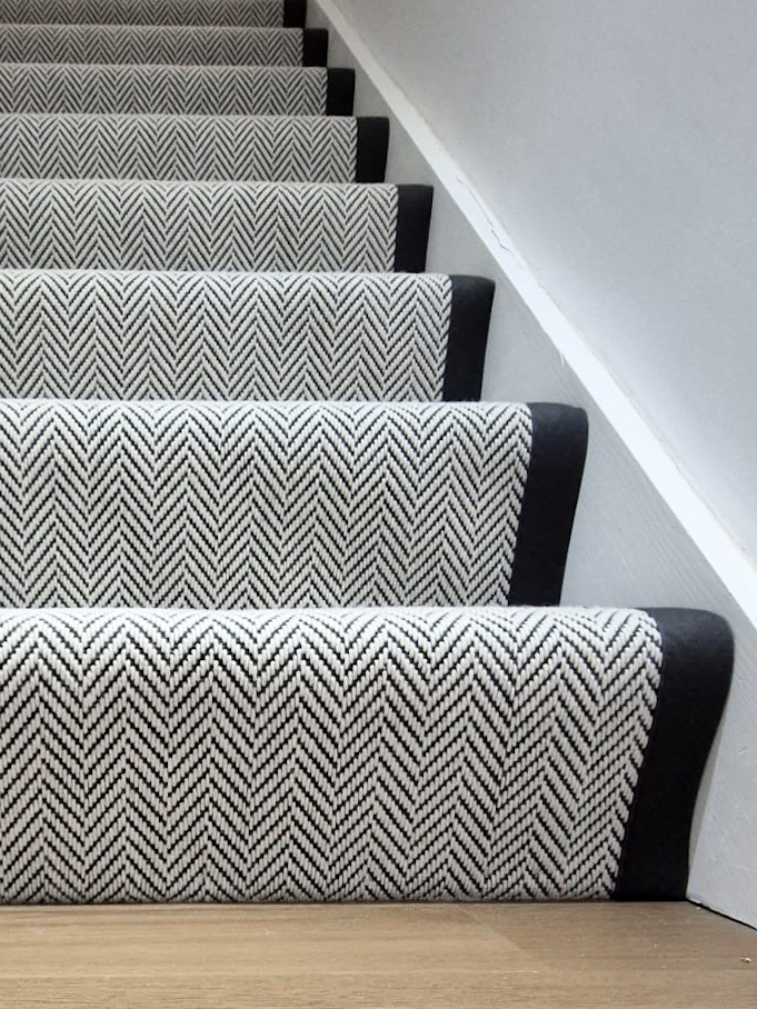 Close-up of a herringbone stair runner with a dark border