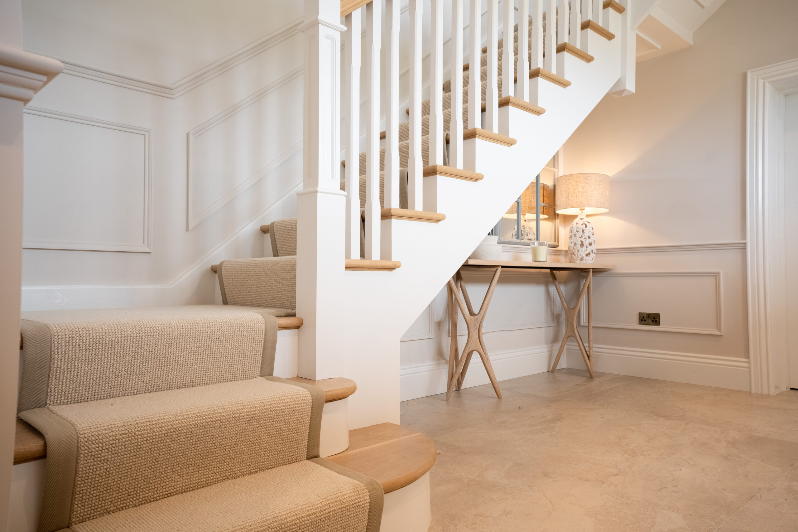 Neutral textured stair runner with tonal edging on a pale timber staircase beside a hallway console