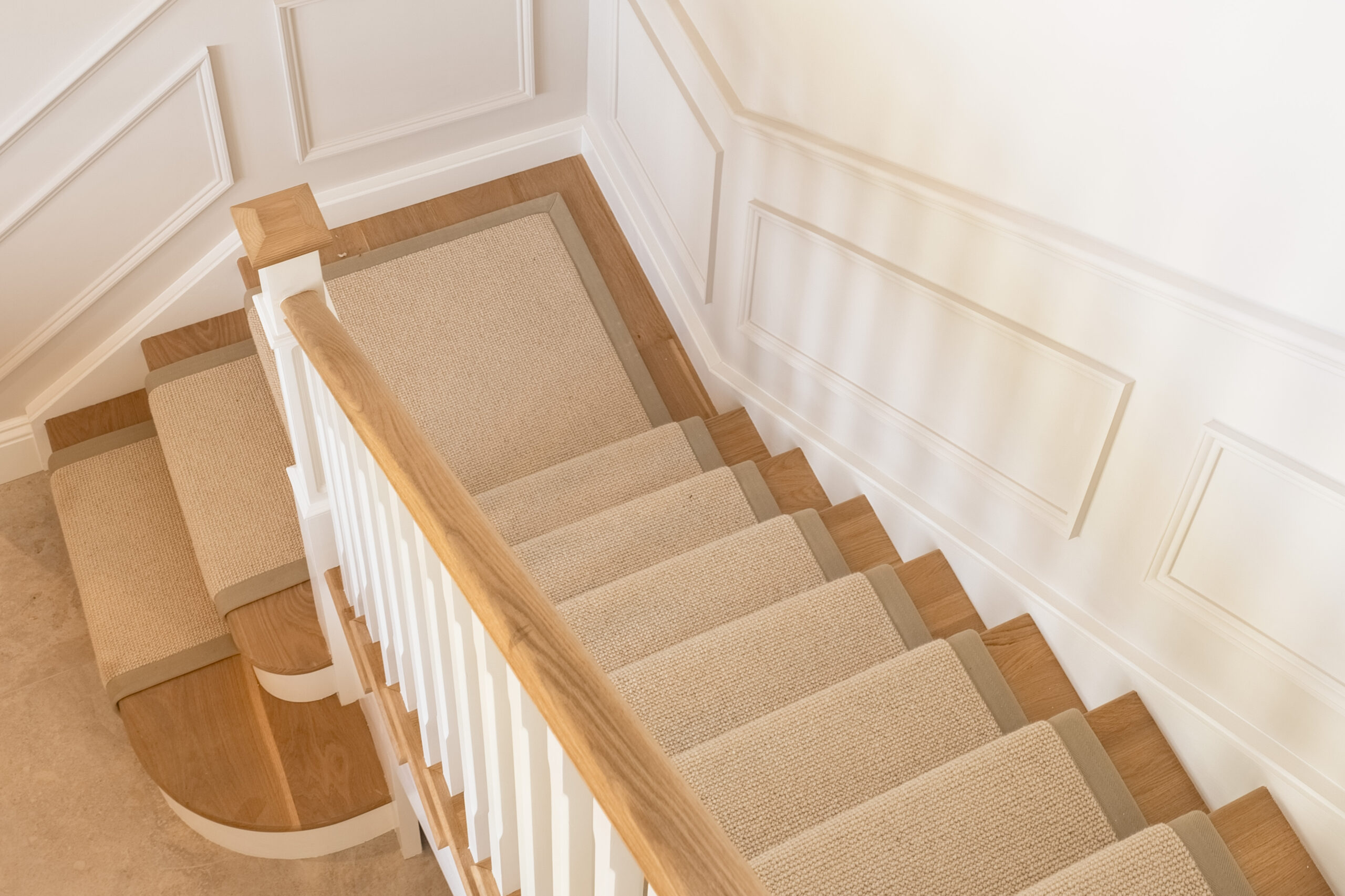 Overhead view of a neutral stair runner with tonal binding following a turning timber staircase