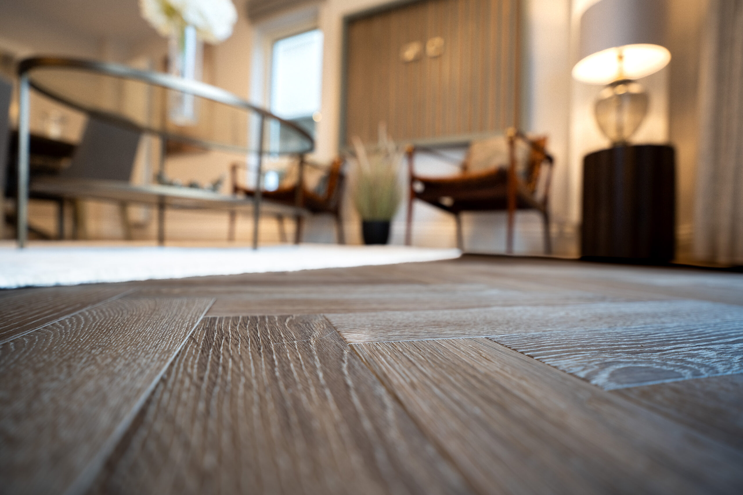 Close-up of herringbone wood flooring in a softly lit living room