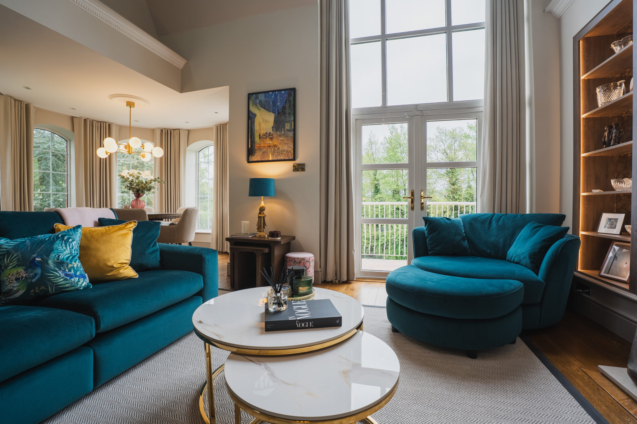 Light-filled living room with a textured rug, wood flooring and teal seating