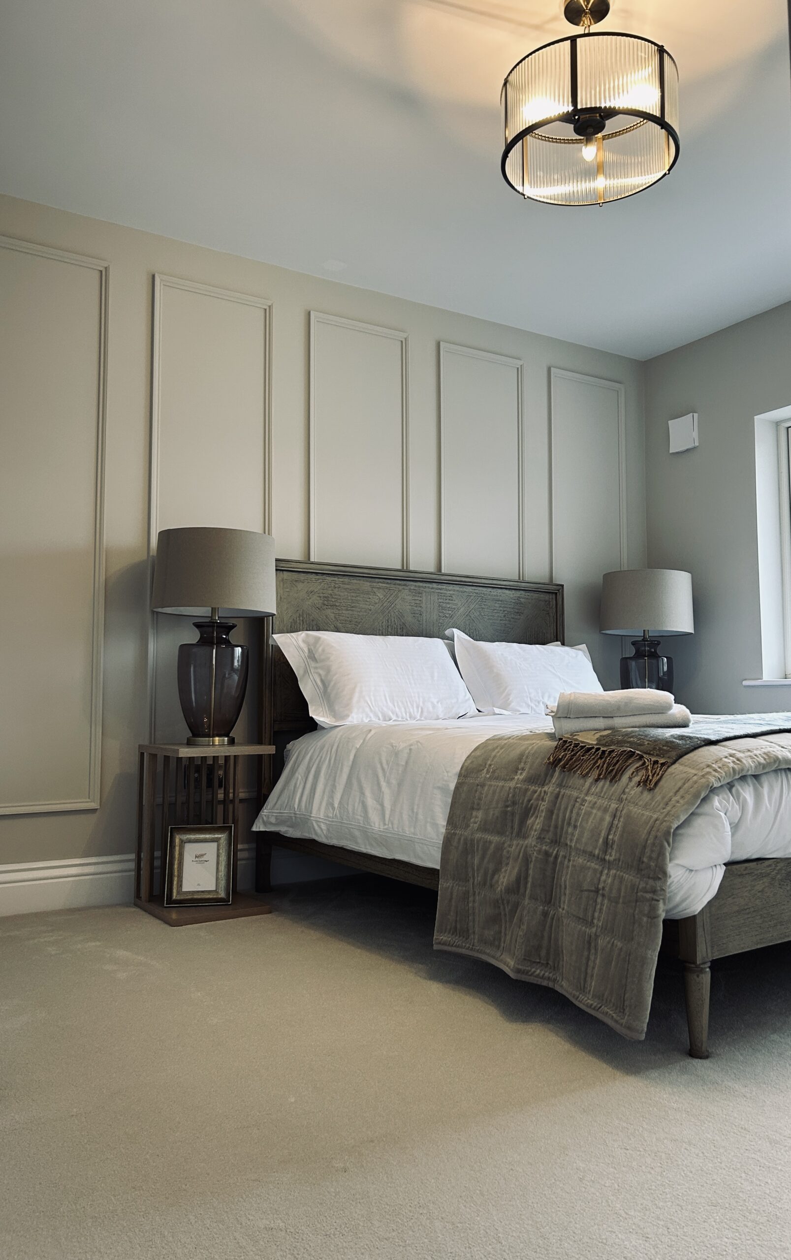 Neutral fitted bedroom carpet beneath a dark timber bed with layered bedding